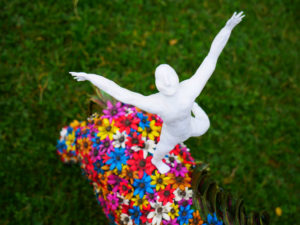 Horse sculpture covered on flowers, with a man standing on its back