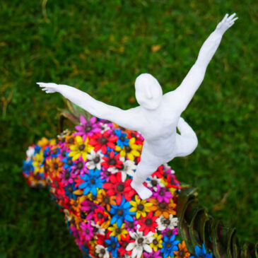 Horse sculpture covered on flowers, with a man standing on its back