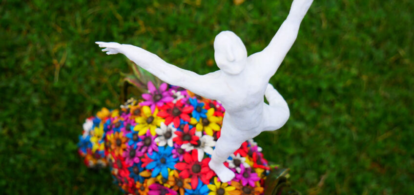 Horse sculpture covered on flowers, with a man standing on its back